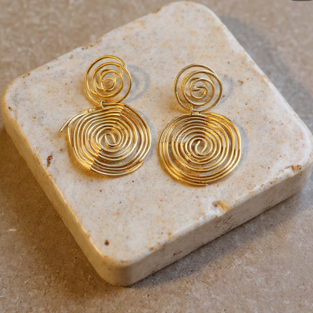 Gold spiral earrings on a stone surface with social media interface elements.