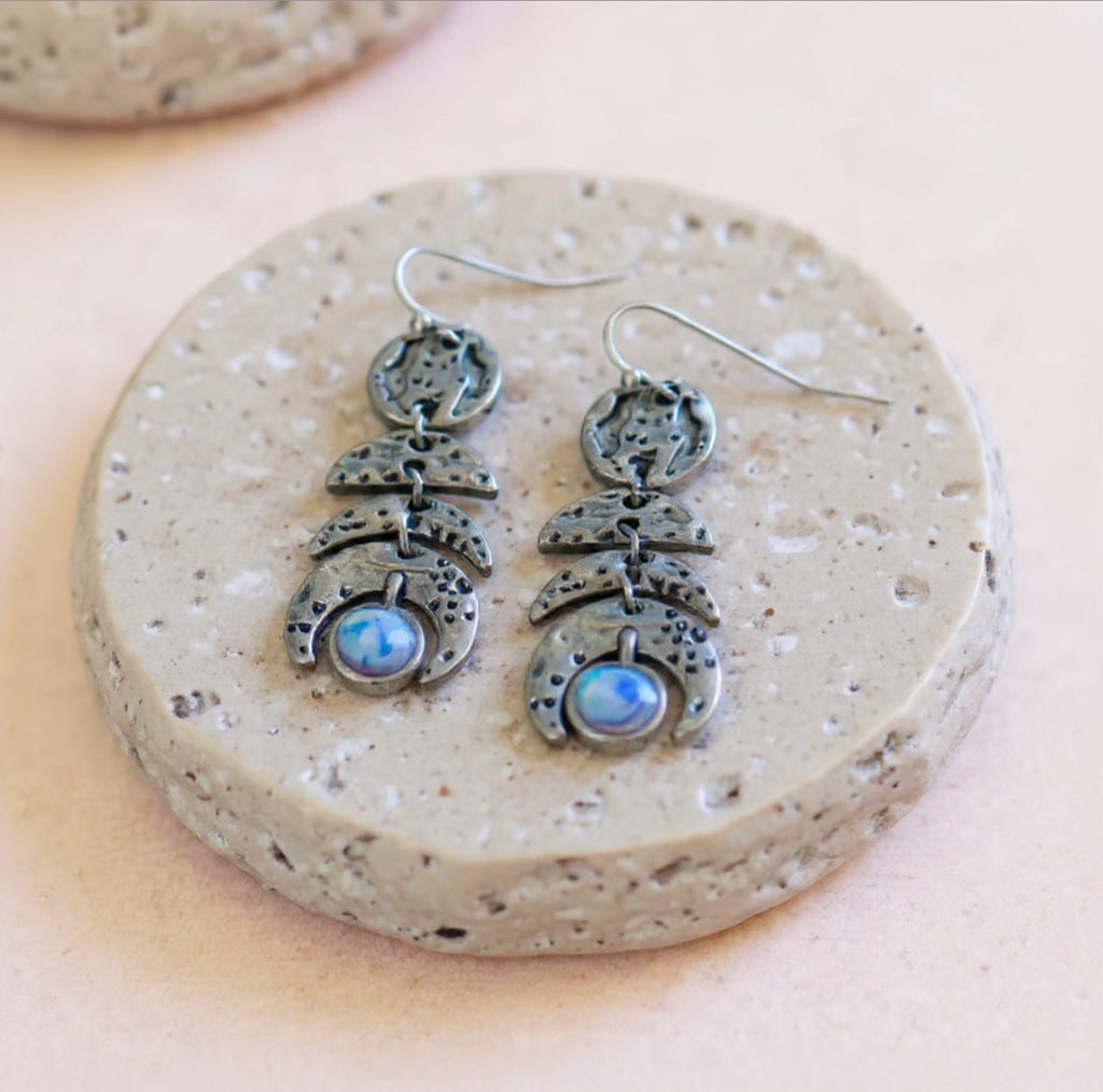 Silver earrings with moonstone stones on a speckled stone surface, bohemian celestial style jewellery in Australia 