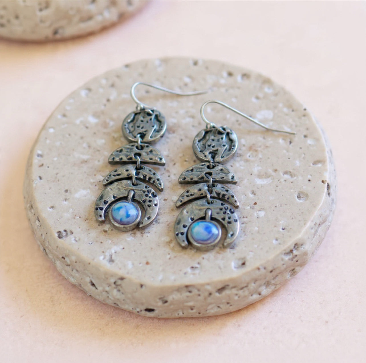 Silver earrings with moonstone stones on a speckled stone surface, bohemian celestial style jewellery in Australia 